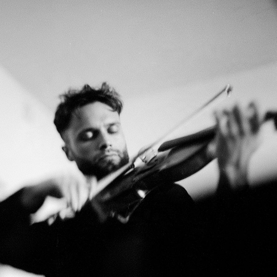 A violinist playing with eyes closed, in black and white